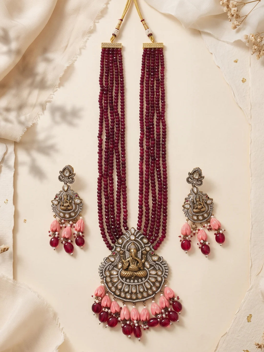 Maroon Ganesha necklace set with a decorative deity pendant, intricate stone embellishments, layered beads and coordinating earrings for ethnic outfits.
