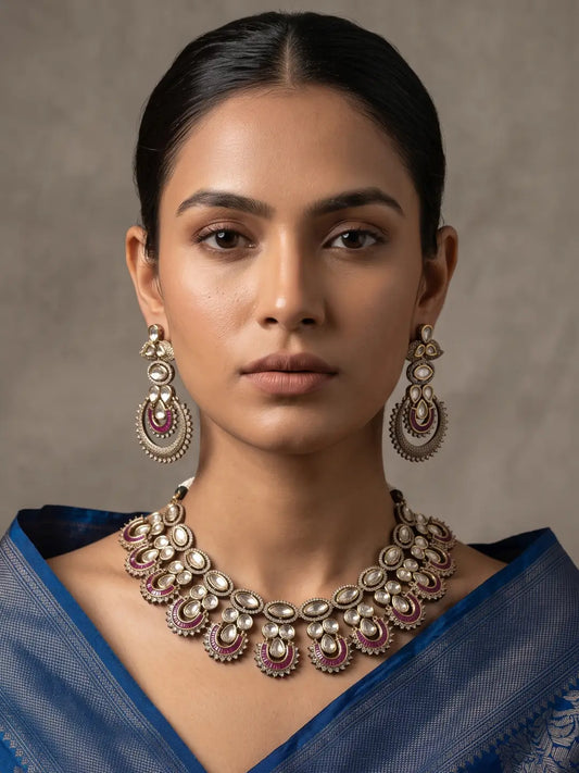 Antique Victorian finish Kundan necklace featuring rich ruby-colored stones, layered detailing, Polki accents and matching statement earrings for a regal bridal look.