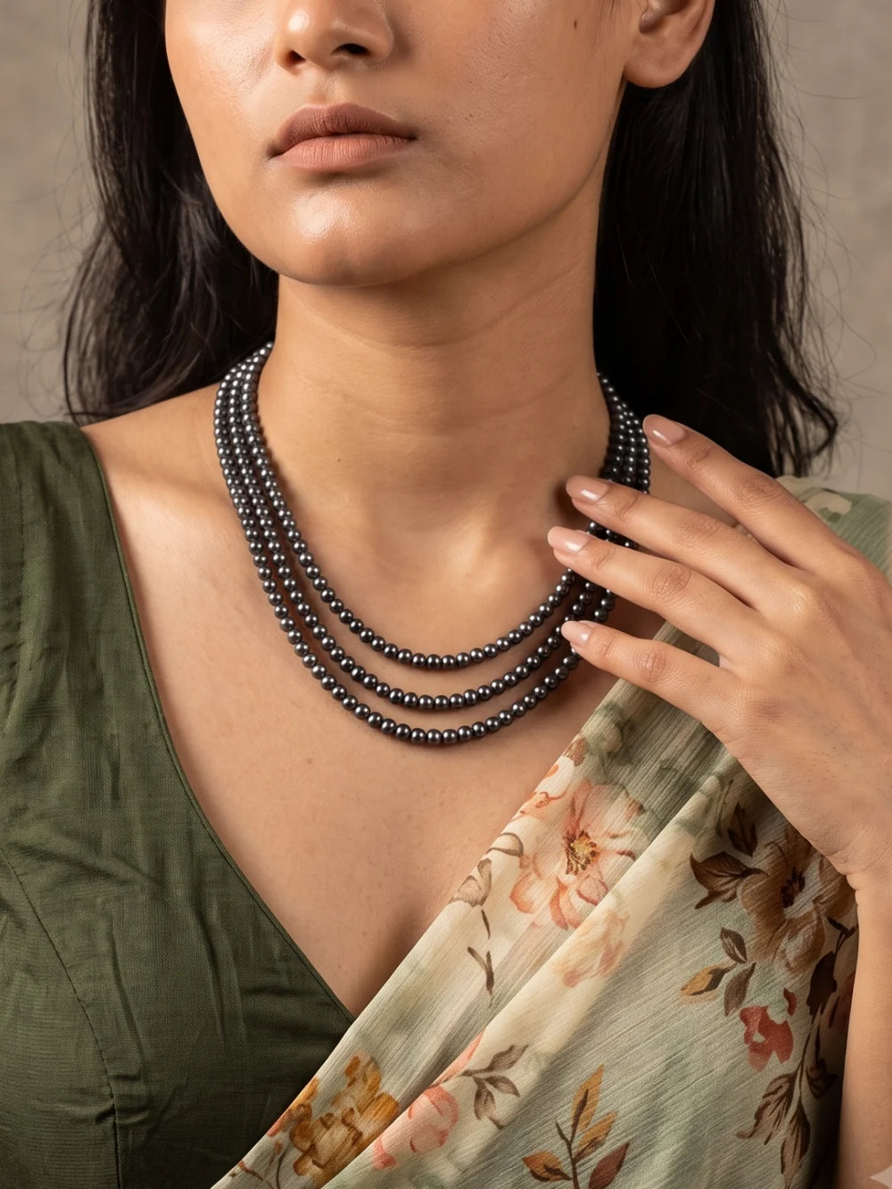 Full view of a layered necklace with black and charcoal grey freshwater pearls arranged in graduated strands and joined by gold-toned connector bars