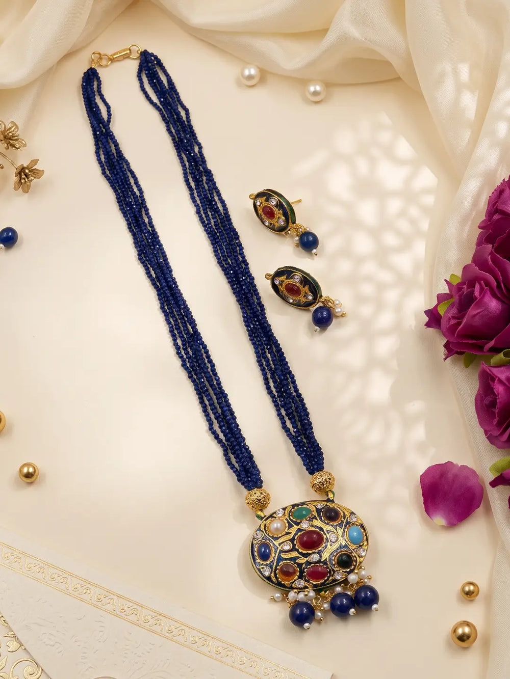 Gold-plated blue necklace set featuring a decorative Navratna Meenakari pendant, layered beads and matching stud earrings.