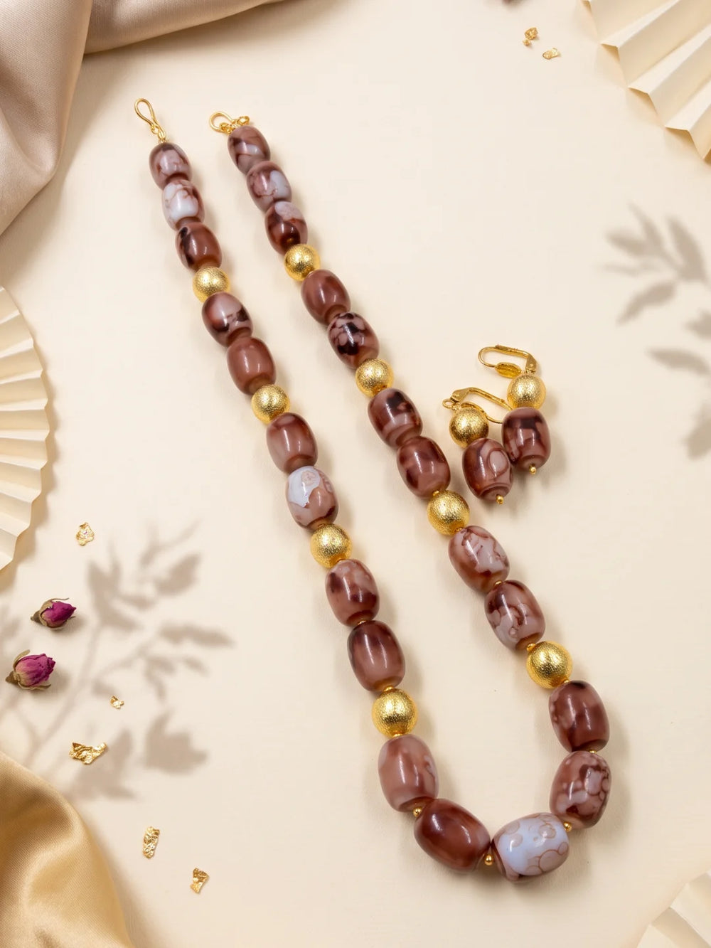Close-up of brown shaded chalcedony cylinder beads with natural-looking colour variation and gold-plated round spacer beads along the layered strands