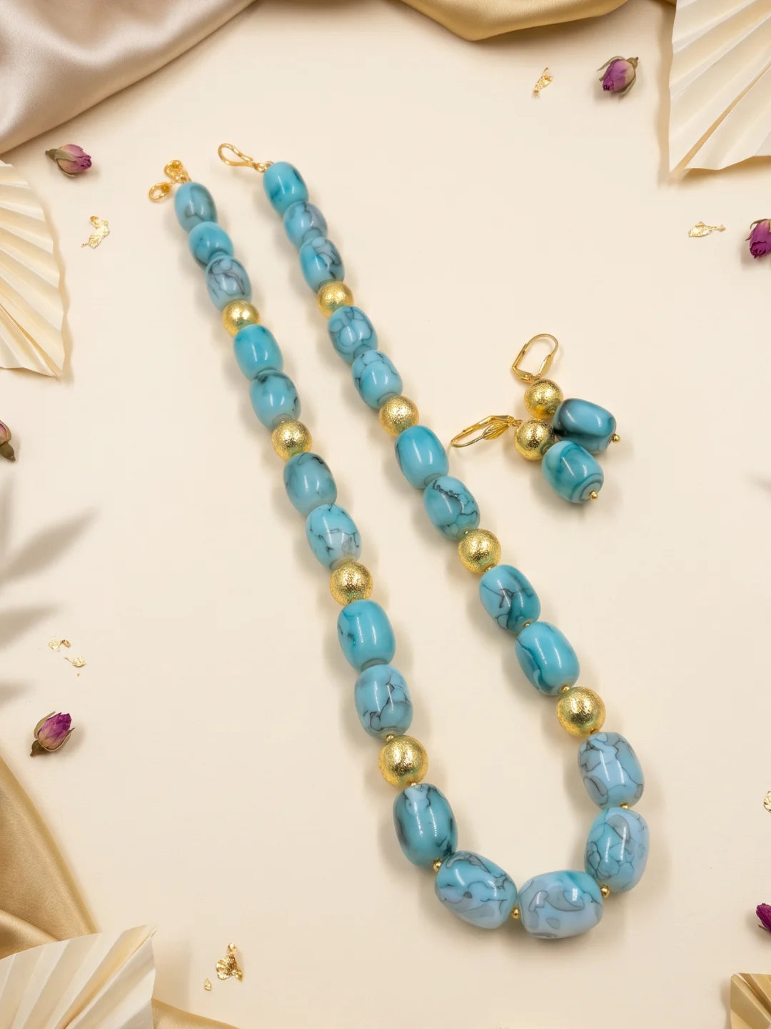 Close-up of sky blue shaded chalcedony cylinder beads with a geometric arrangement and gold-plated round spacer beads adding contrast between the stones