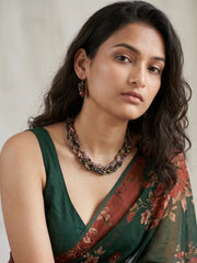 Close-up of smooth rectangle-shaped tourmaline beads in black, translucent green, honey, champagne and brown shades with small gold-tone spacer beads