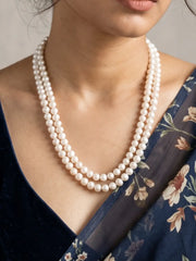 Close-up of evenly arranged round ivory-white freshwater pearl beads showing a smooth, polished finish and soft natural-looking sheen on both strands