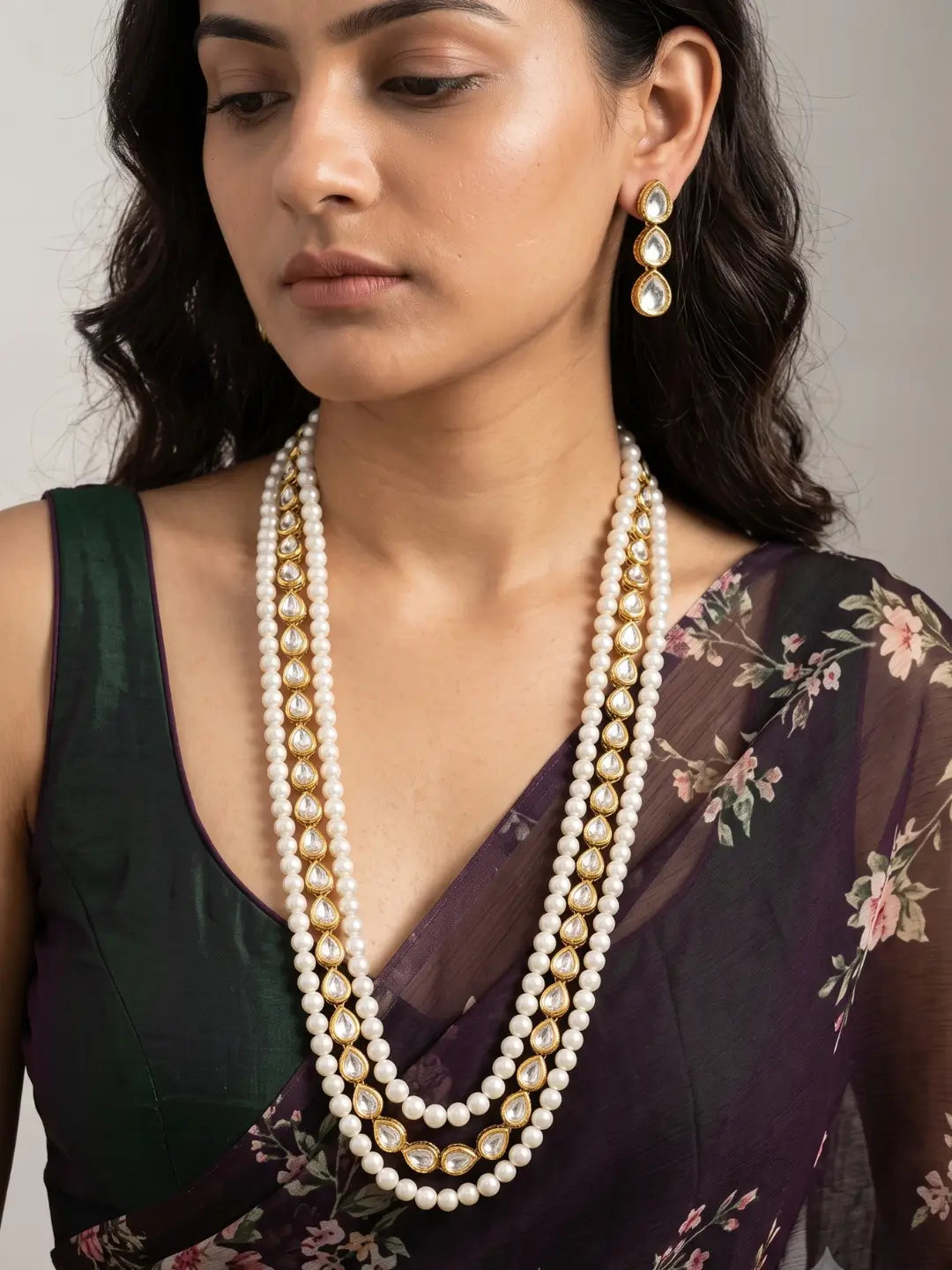 Close-up of the gold-tone teardrop kundan-style stones arranged in a floral-inspired pattern at the centre of two luminous round white pearl strands