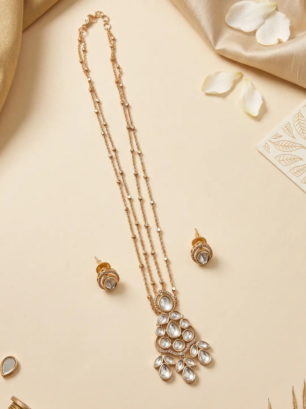 Close-up of a white teardrop pendant framed with Polki and CZ stones, paired with matching stud earrings in a gold plated finish.