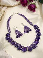 Close view of glossy deep-purple faceted amethyst teardrop beads beside delicate strands of smaller purple amethyst beads with silver-tone accents