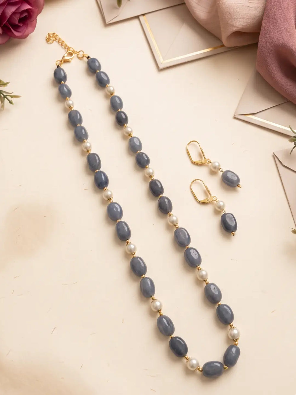 Close view of glossy grey box-shaped jade beads with faux pearls and gold-tone accents on a single-strand necklace