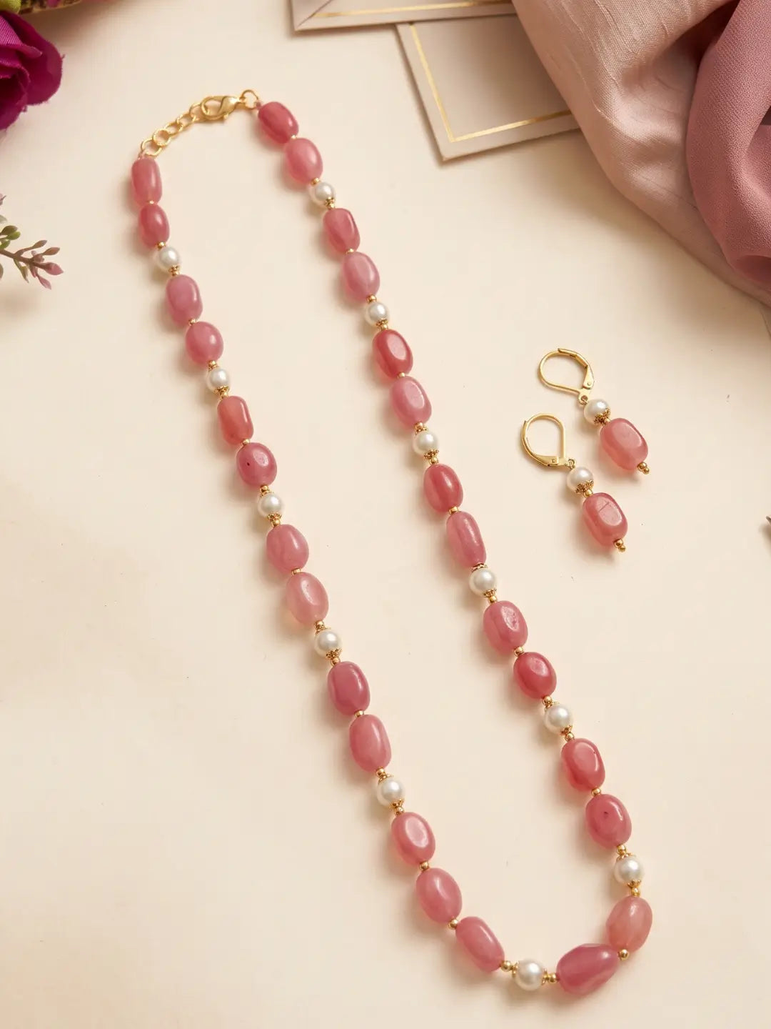 Close view of glossy pink box-shaped jade beads paired with faux pearls and gold-tone accents on a single-strand necklace