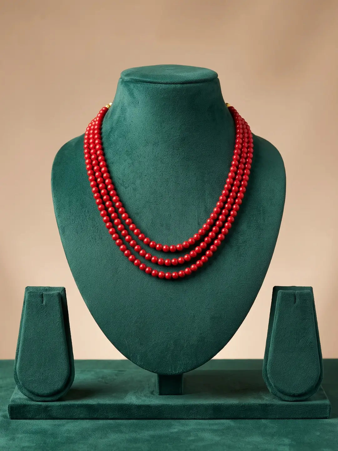 Close view of glossy polished red coral beads in rich red tones with elegant gold-tone end caps at the ends of the layered strands