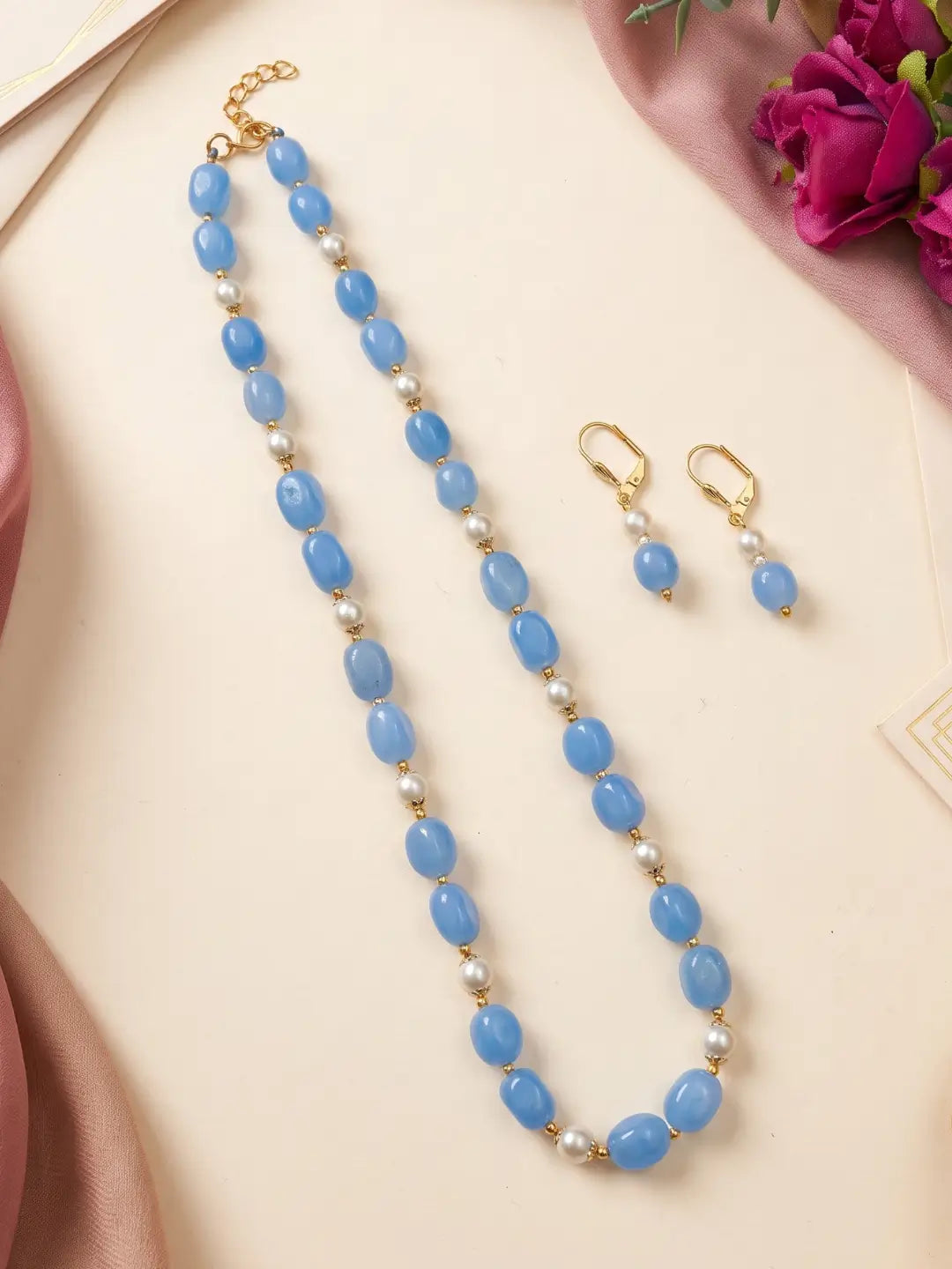 Close view of glossy blue box-shaped jade beads with faux pearls and gold-tone accents on a single-strand mala