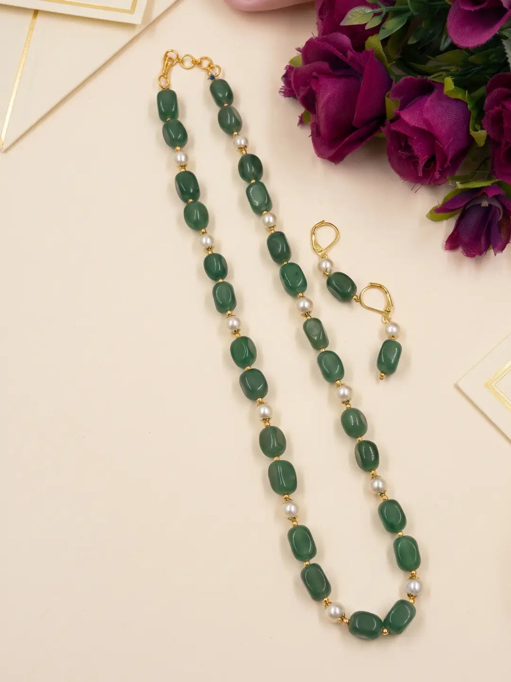 Close view of glossy green box-shaped jade beads with faux pearls and gold-tone accents on a single-strand mala