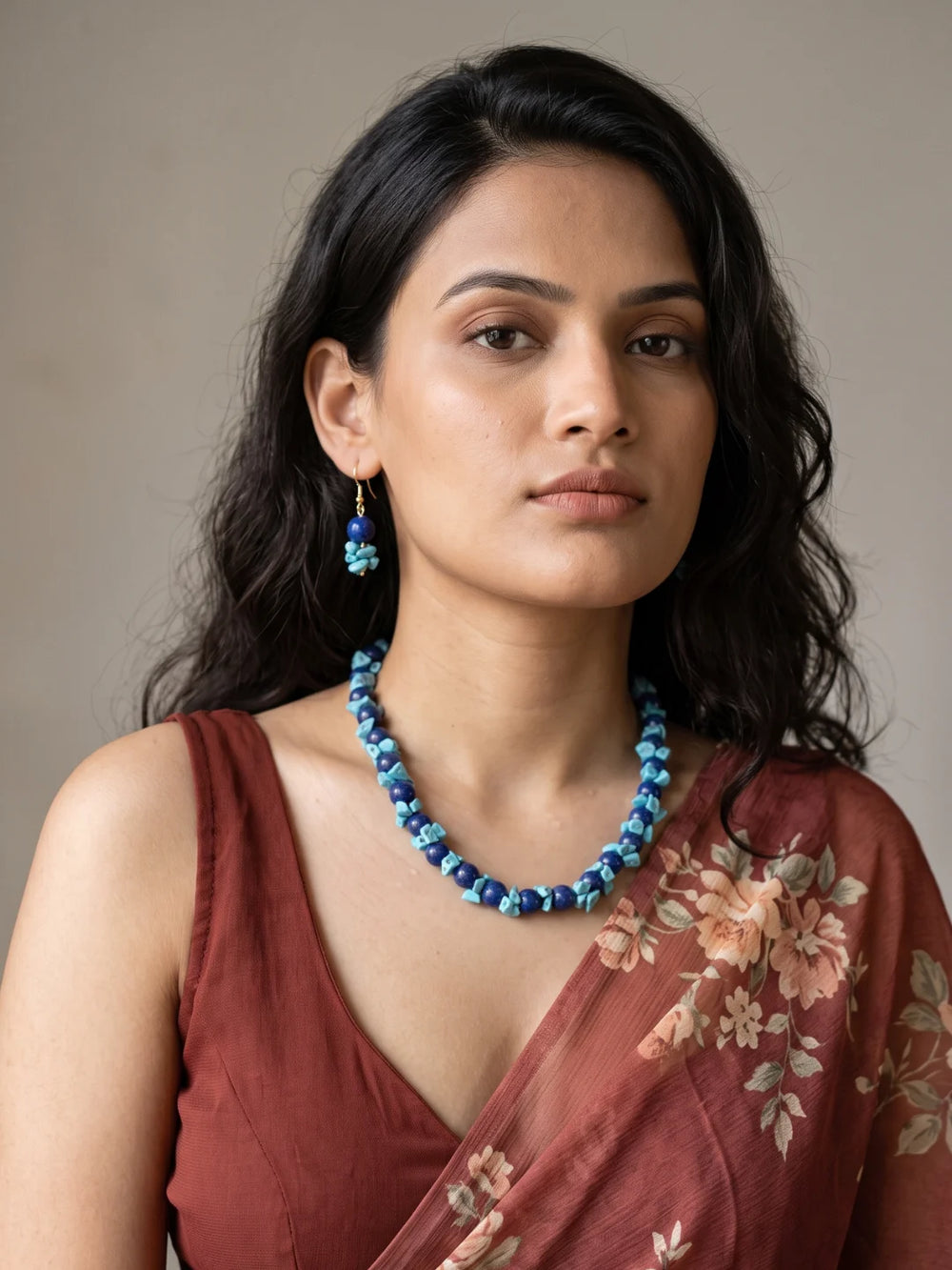 Close-up of smooth round deep blue lapis lazuli beads, irregular bright turquoise chips and small silver-tone spacer beads along the layered strands