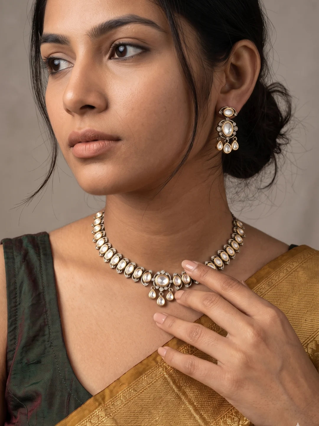 Dual tone Polki necklace and earrings with oval motifs, contrasting stone details, clear CZ accents, and a Victorian-inspired design.