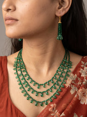 Full view of a layered emerald green necklace with glossy faceted beads and translucent teardrop accents, shown with matching drop earrings
