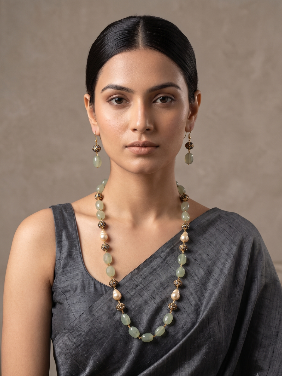 A woman wearing a Handcrafted Gemstone Long Green Beaded Necklace And Earring Set on a gray saree | Elegant Ethnic Jewellery