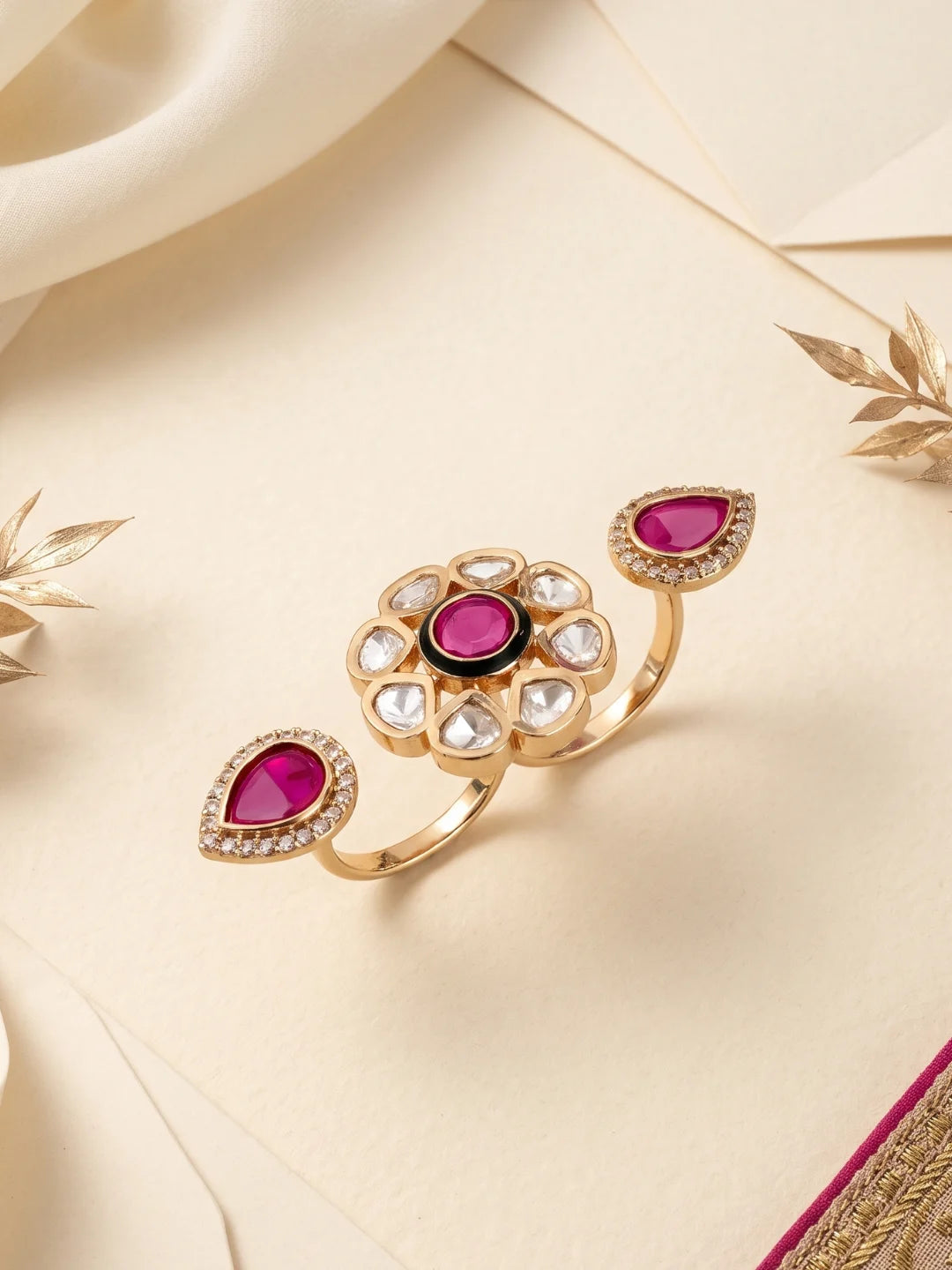 Ruby pink statement ring featuring an open dual-finger design, floral Polki detailing, CZ stones and a gold-plated setting.