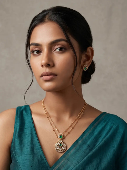 Gold-plated jewellery set featuring a teardrop Polki pendant with green coloured stones and matching stud earrings for festive and occasion styling