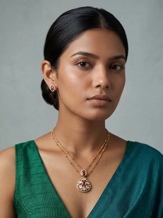 Gold-plated jewellery set featuring a teardrop Polki pendant with red coloured stones and matching stud earrings for festive and occasion styling