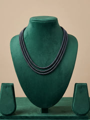 Detail of the gold-toned connector bars holding the layered black and grey pearl strands together, contrasting against the darker pearls
