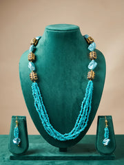 Detail of gold-toned cylindrical metallic beads with black detailing set between turquoise and blue beads on the necklace strands