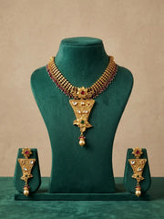 Gold-toned traditional jewelry set displayed on a dark green velvet mannequin bust, including a necklace with a large triangular pendant and matching earrings, set against a warm beige background.