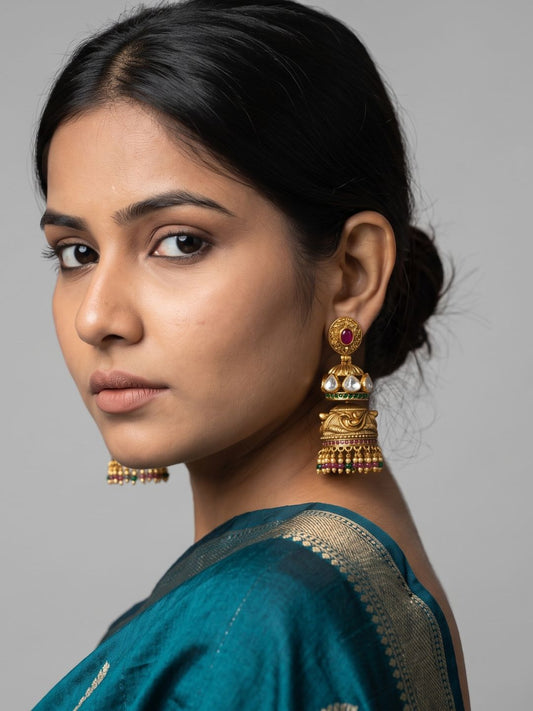 Traditional double Jhumka earrings featuring Kundan stonework, ruby accents, intricate floral carvings and an antique gold finish.