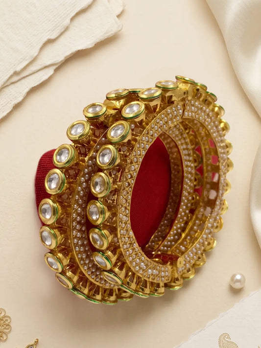 Gold plated Kundan Pacheli bangles with pearl accents, green Meenakari details and Kundan-style stones for bridal and festive outfits.