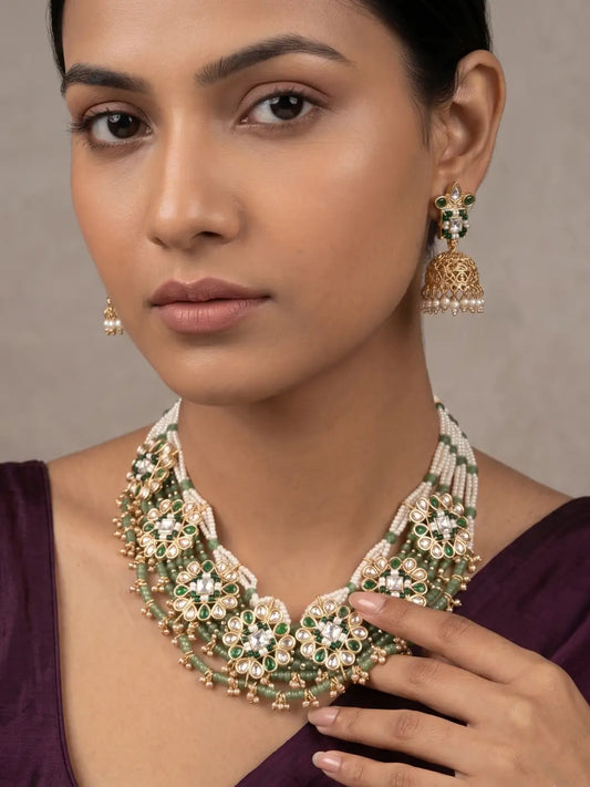 Green beaded Kundan necklace set with layered pearl strands, gold-tone floral detailing and matching jhumka earrings for ethnic occasions