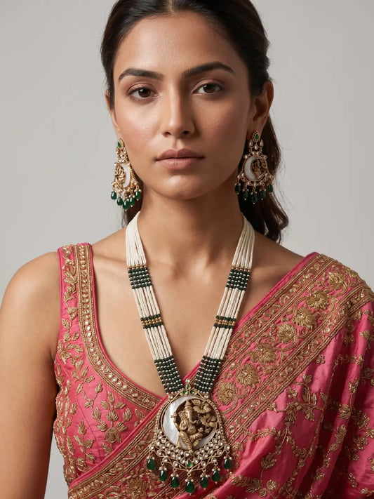 Indian woman wearing a gold-plated green Ganpati temple jewellery set with layered pearl strands, ornate pendant, green accents and matching earrings