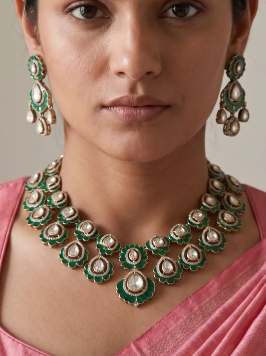 Woman styled in a green Kundan Polki necklace featuring repeating floral motifs, luminous teardrop stones, green accents, statement earrings and a matching maang tikka.