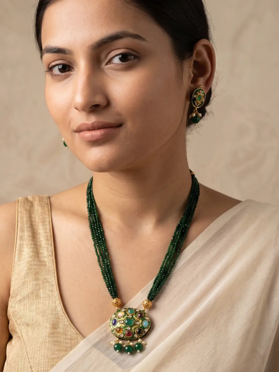 Gold-plated green necklace featuring a multicolour Navratna Meenakari pendant, layered bead strands and matching stud earrings.