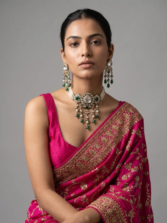 Close view of a woman wearing a green Polki choker with intricate Victorian-inspired detailing, layered pearl accents, coloured drops and statement earrings.