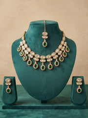Green Polki Jewelry set with necklace and earrings on a green mannequin bust against a beige background