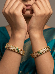 A woman wearing a Gold-plated green stones and kundan-studded bangles on both her wrists. 