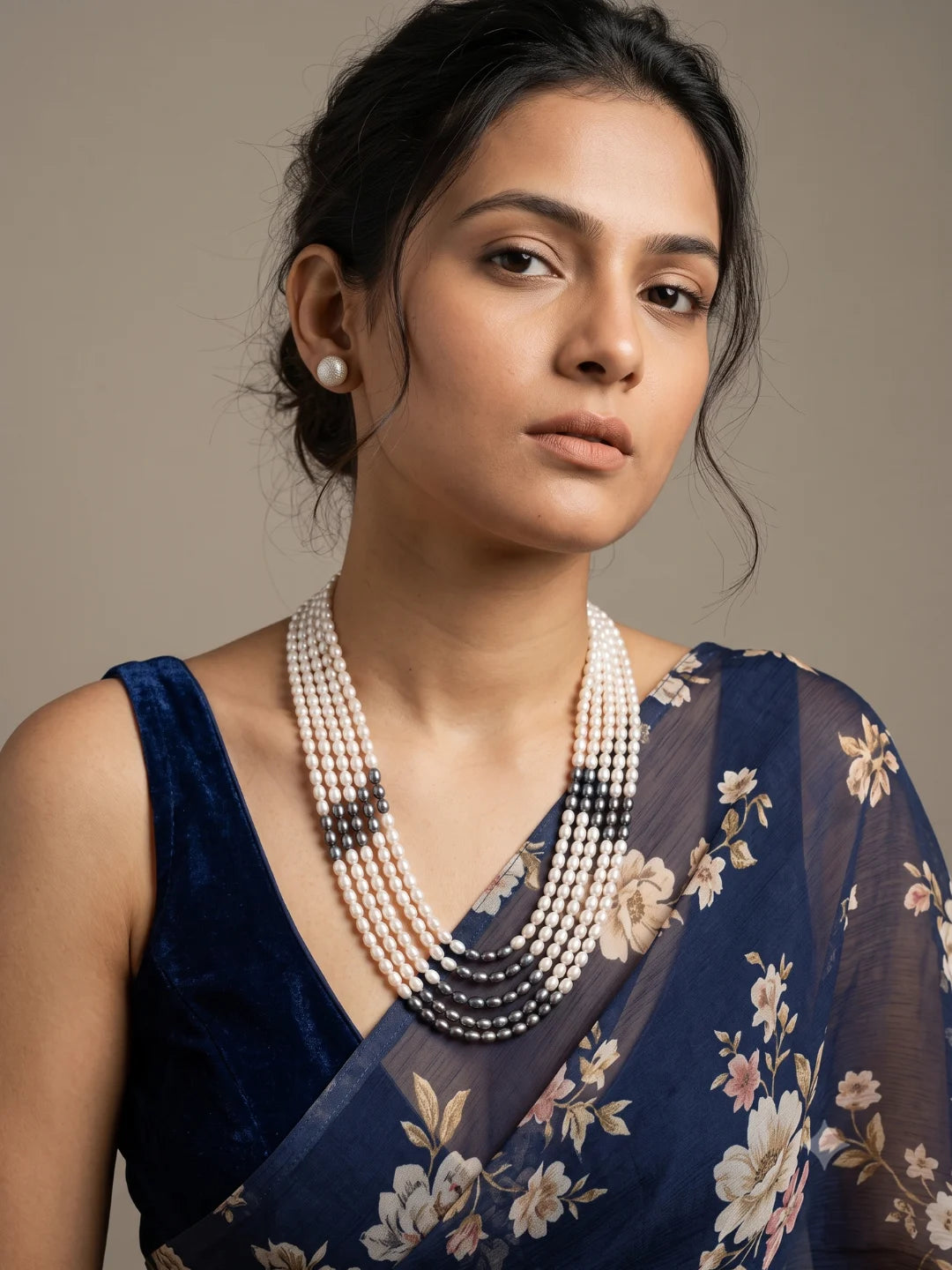 Full view of a layered necklace with lustrous white and grey freshwater pearls in multiple strands, shown with matching pearl stud earrings