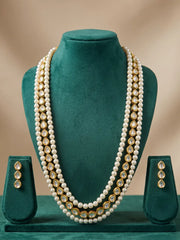 Pair of gold-tone teardrop-shaped earrings with green detailing, shown as the matching earrings of the white pearl and kundan necklace set