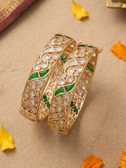 Decorative gold-plated polki kundan bangles with green stones on a beige background