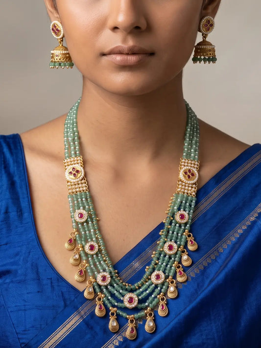 Layered green jade beaded necklace set with antique gold Kundan brooches, ruby-coloured accents and matching jhumka earrings for ethnic wedding looks