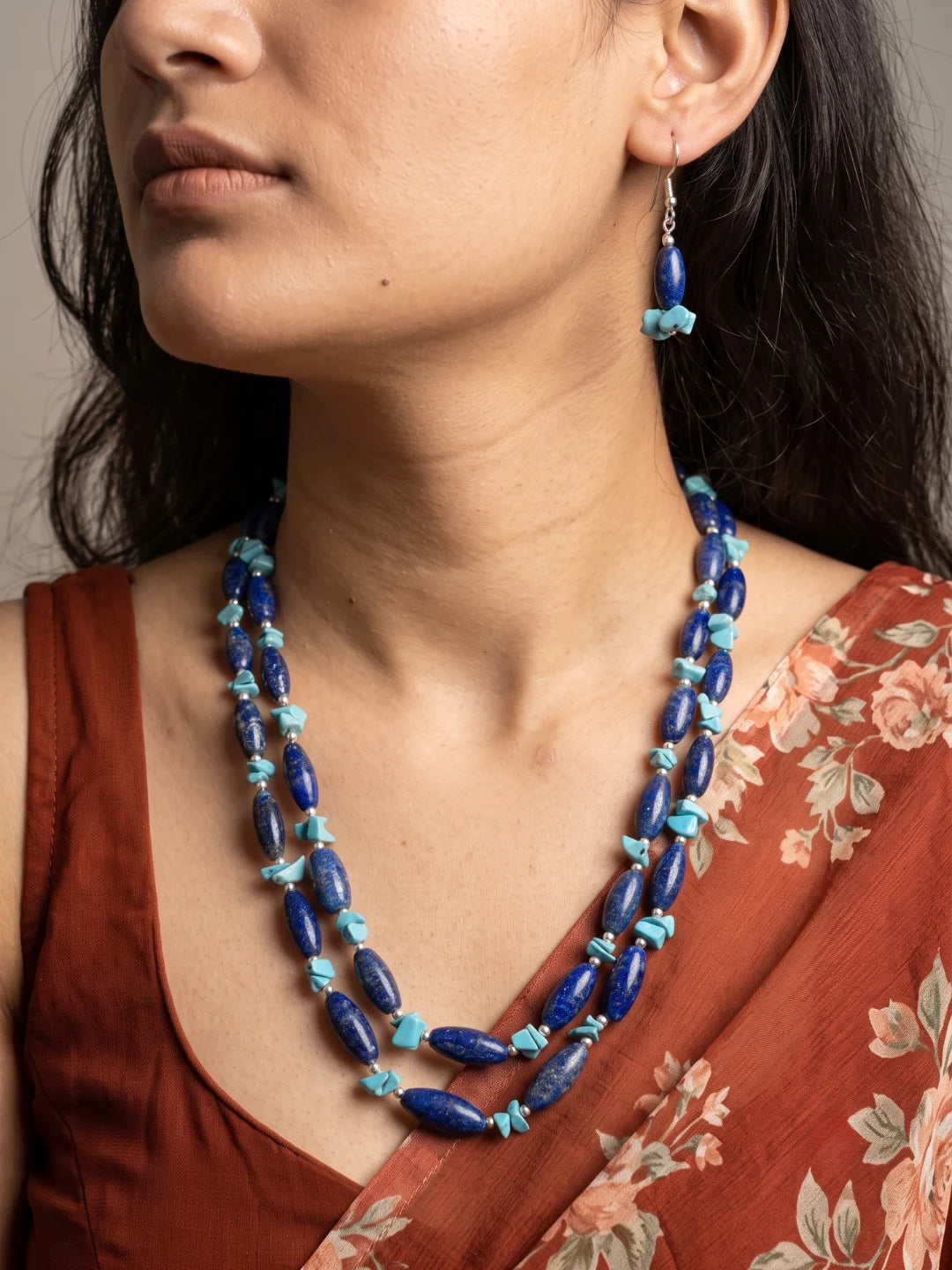 Layered necklace of royal-blue lapis lazuli beads with bright turquoise chip beads and silver-tone spacers, laid out beside a pair of drop earrings