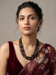 Multi-strand necklace of smooth tourmaline beads in black, green, brown and golden yellow with gold-tone spacers, laid out in a full curved view