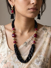Multi-strand red and black beaded necklace set with gold-tone spherical accents, shown with matching drop earrings with black beaded tassels