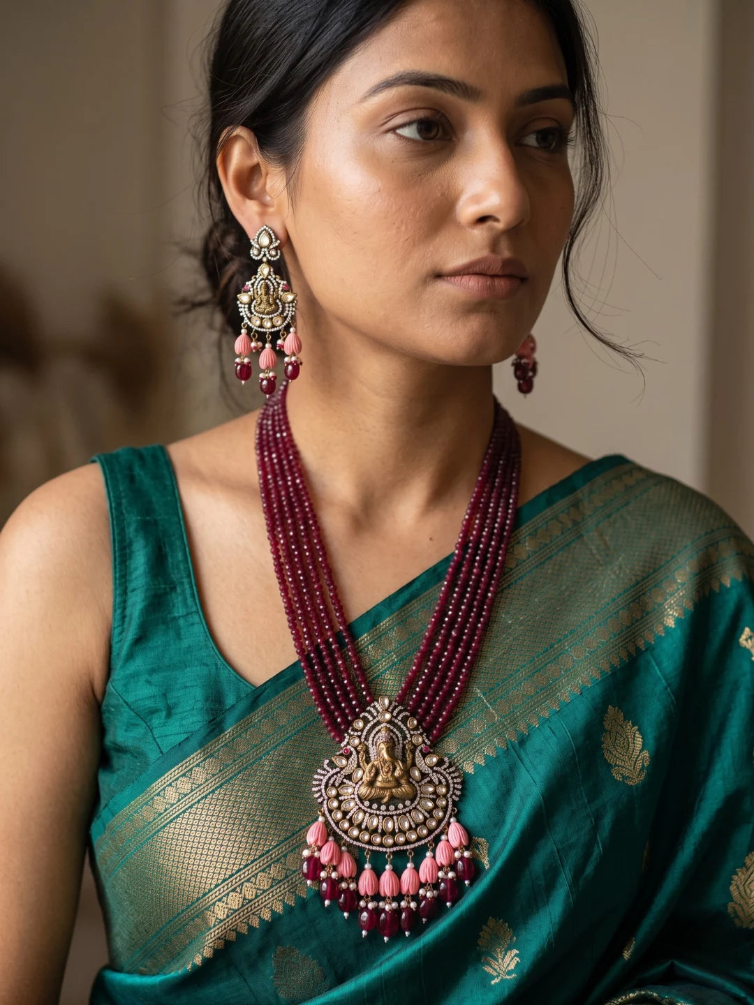 Maroon Ganesha temple necklace set featuring an ornate Ganpati pendant, antique-style detailing, layered jade beads and matching traditional earrings.