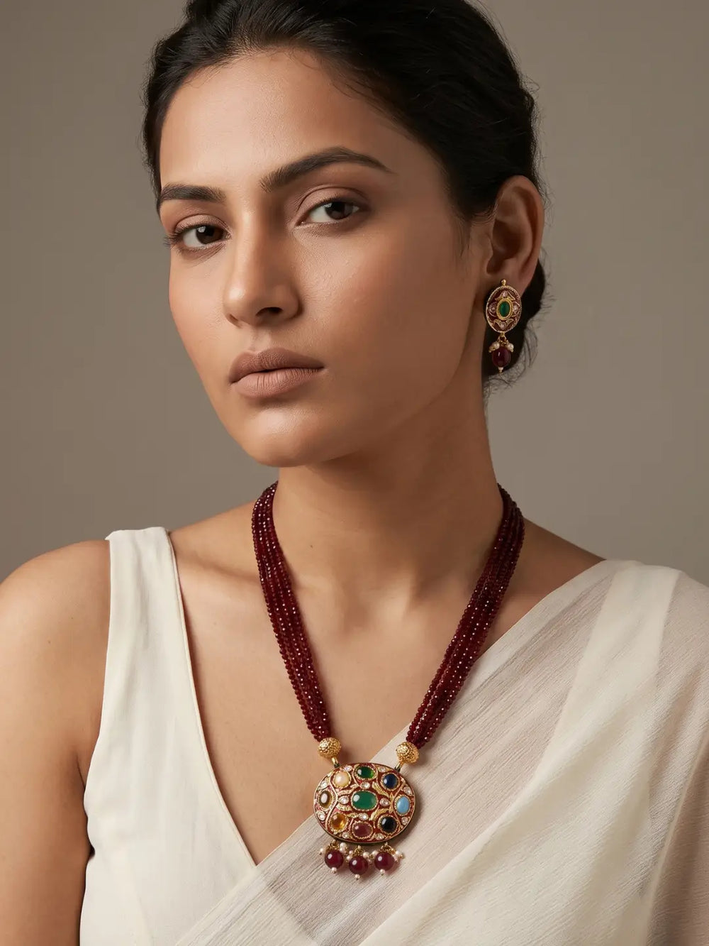 Maroon layered bead necklace with a decorative Navratna Meenakari pendant and matching stud earrings for ethnic outfits.

