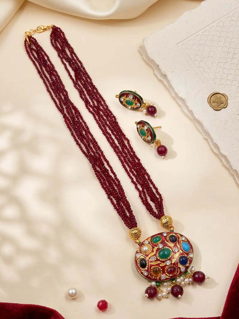 Gold-plated maroon necklace featuring a multicolour Navratna Meenakari pendant, layered beads and matching stud earrings.
