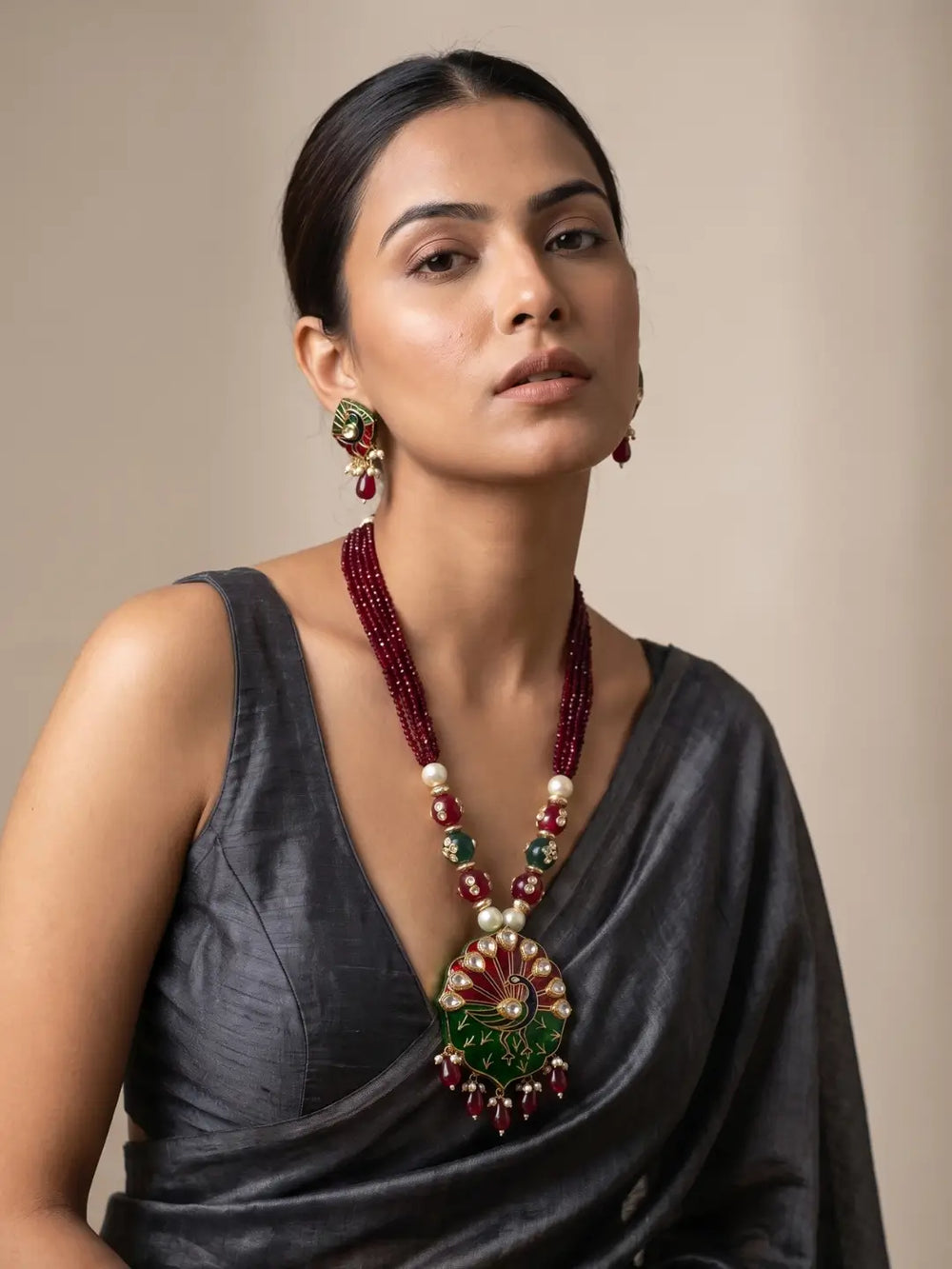 Close-up of the maroon variant's peacock-inspired pendant with vibrant red, green and blue enamel work, Kundan accents and traditional gold-tone detailing.