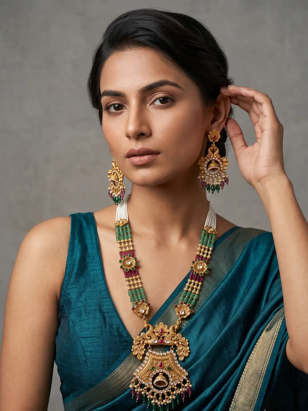 Matching antique gold earrings with intricate floral motifs, sparkling stone accents and dangling green and maroon beads designed to complement the necklace.
