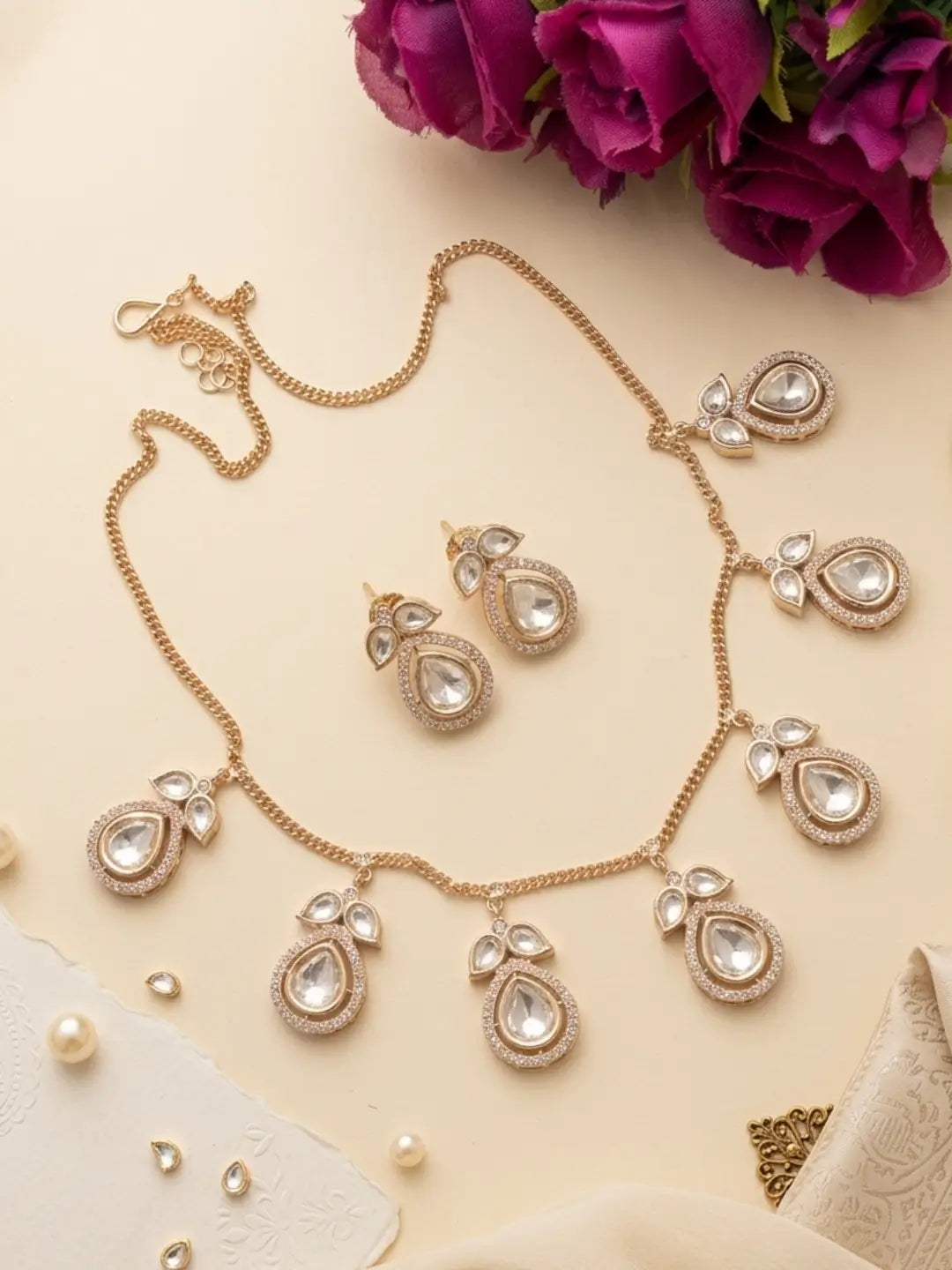 Matching floral stud earrings paired with a gold-tone chain Polki necklace featuring clear Kundan-style stones and delicate teardrop accents.