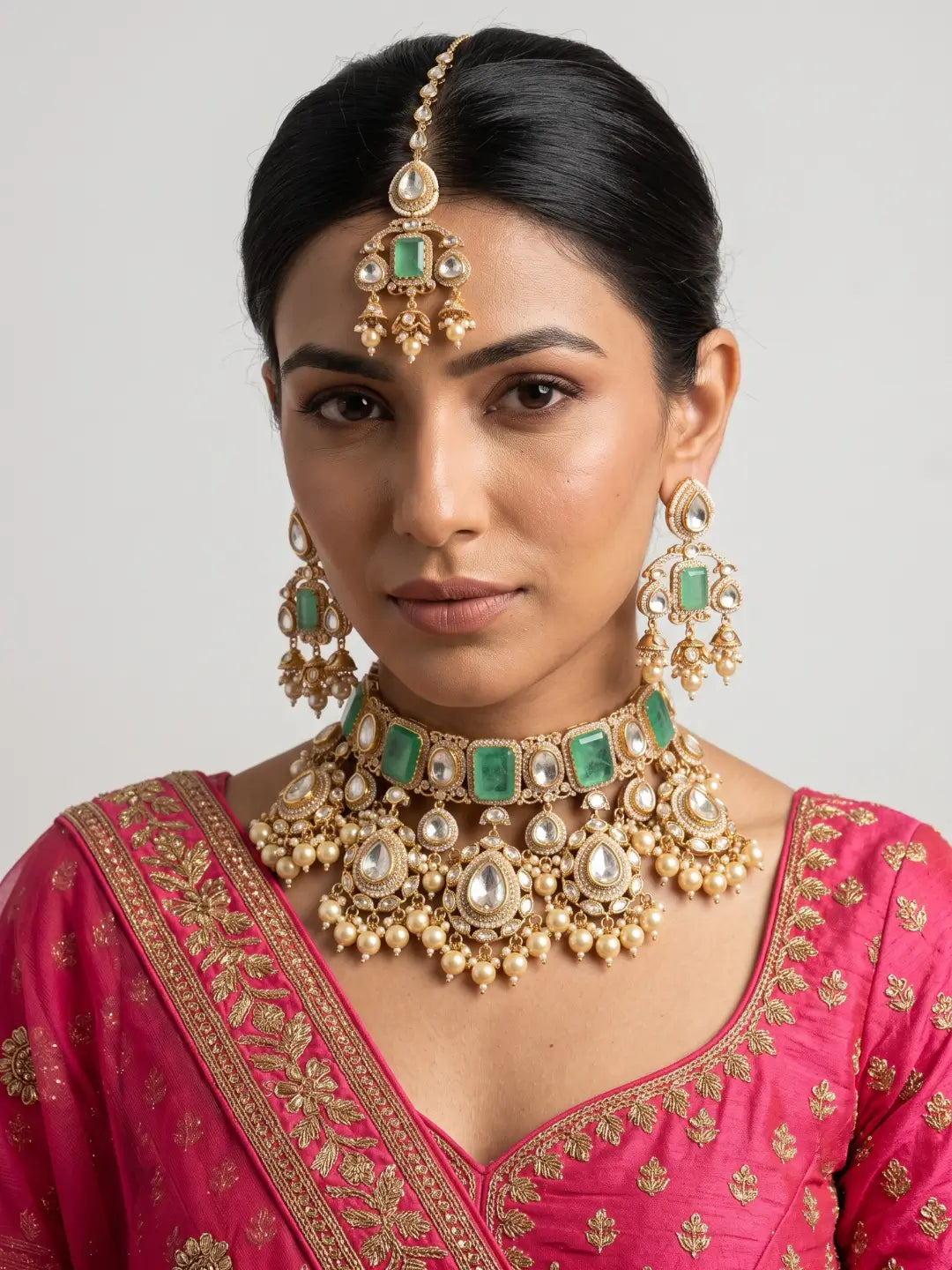 Mint green bridal earrings featuring green doublet stones, white stone accents, intricate gold-tone detailing and delicate dangling pearl drops.