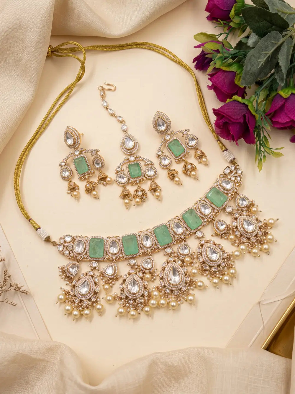 Coordinated mint green maang tikka featuring green doublet stones, white Kundan-style detailing, gold-tone ornamentation and pearl embellishments.